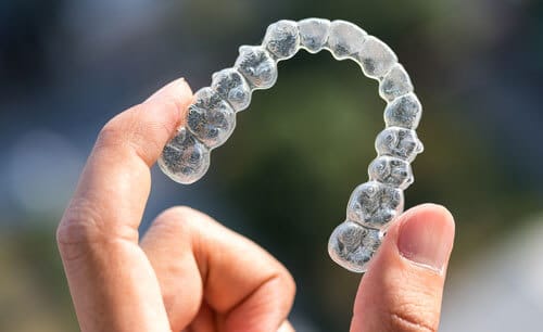 The Dental Studio Pros Of Invisalign Close Up Shot Of Hand Holding An Invisalign