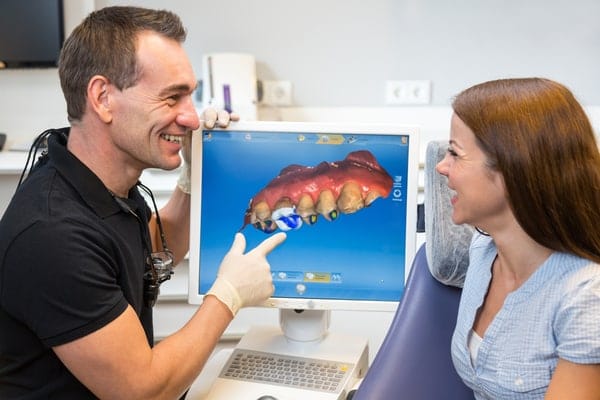The Dental Studio CEREC Restorations Dentist Explaining 3D Image Of Tooth To Patient