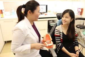 dentist explaining how to prevent Teeth & Gums Disease For Lifetime – the dental studio singapore