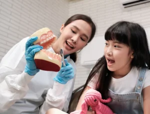 dentist showing how to brush teeth to a child
