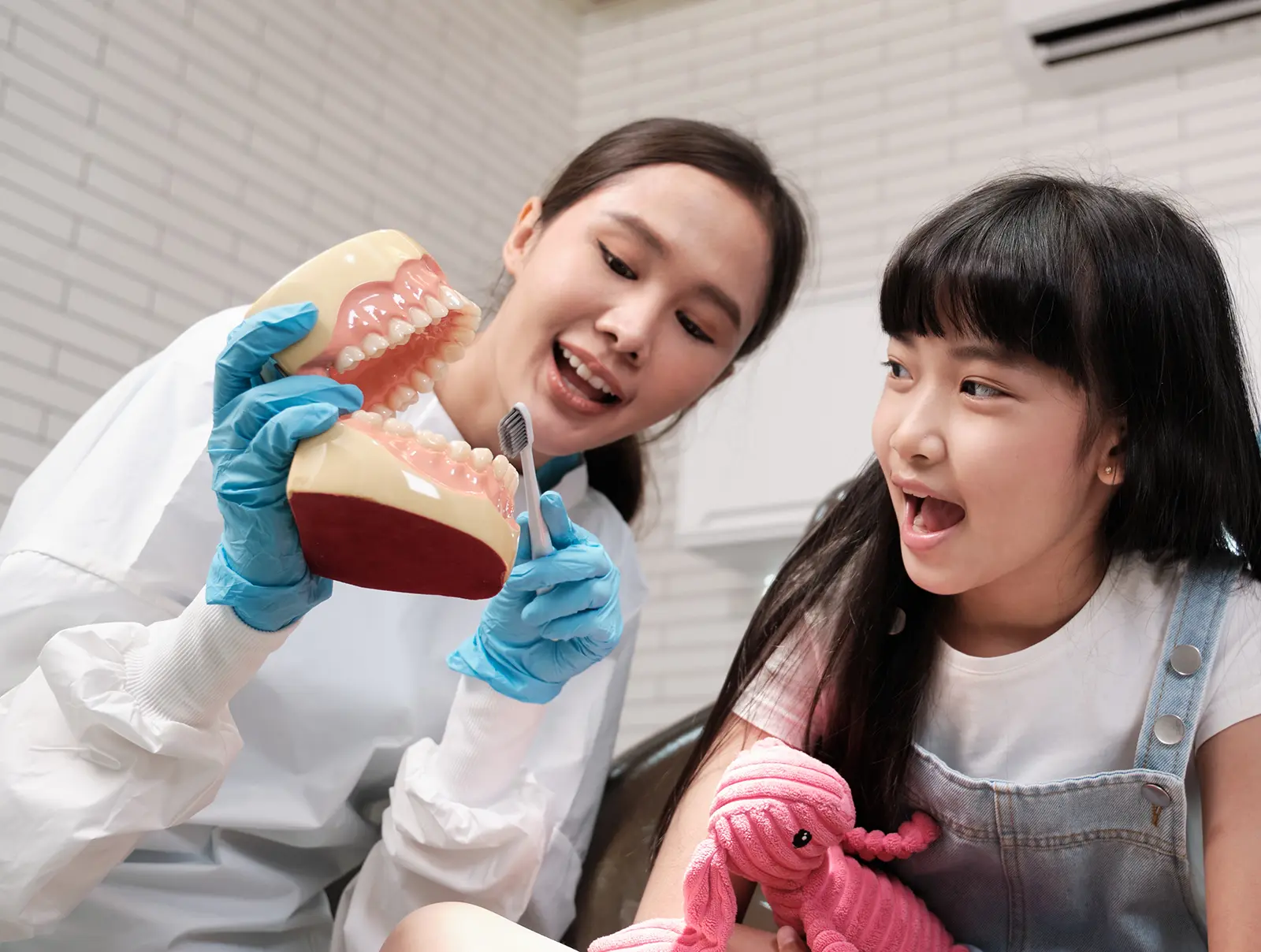 dentist showing how to brush teeth to a child
